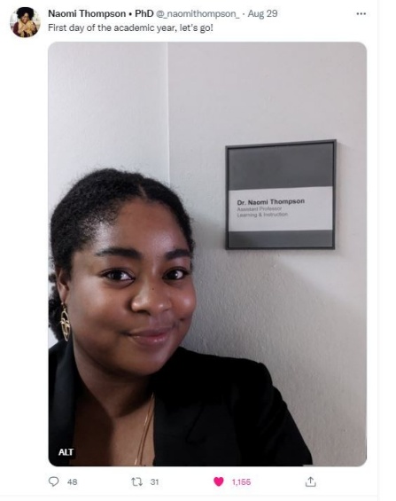 Naomi Thompson pictured in a selfie next to her office door nameplate in Baldy Hall. 