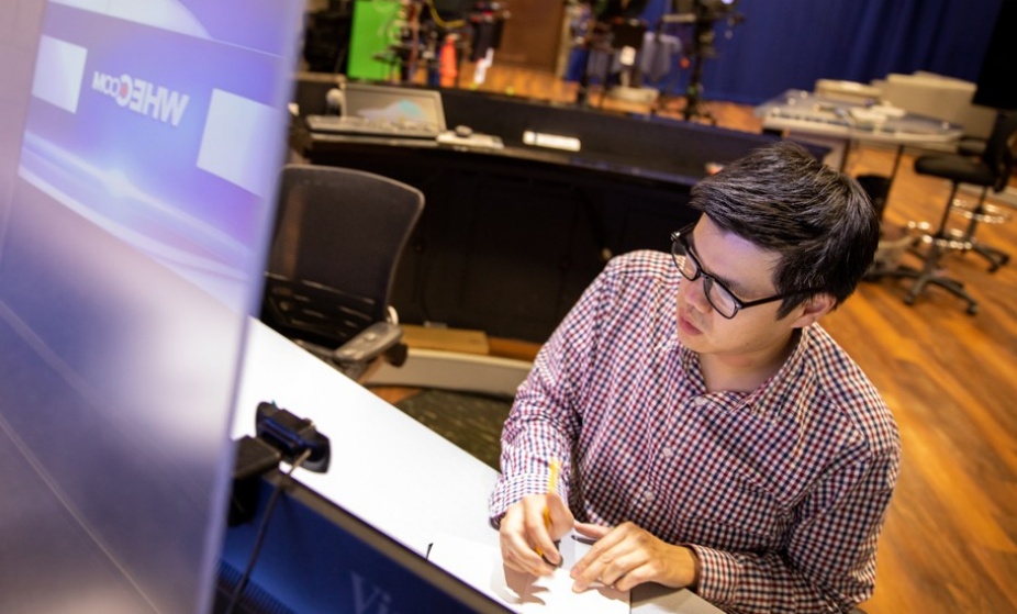 Carl Lam working at a news desk. 