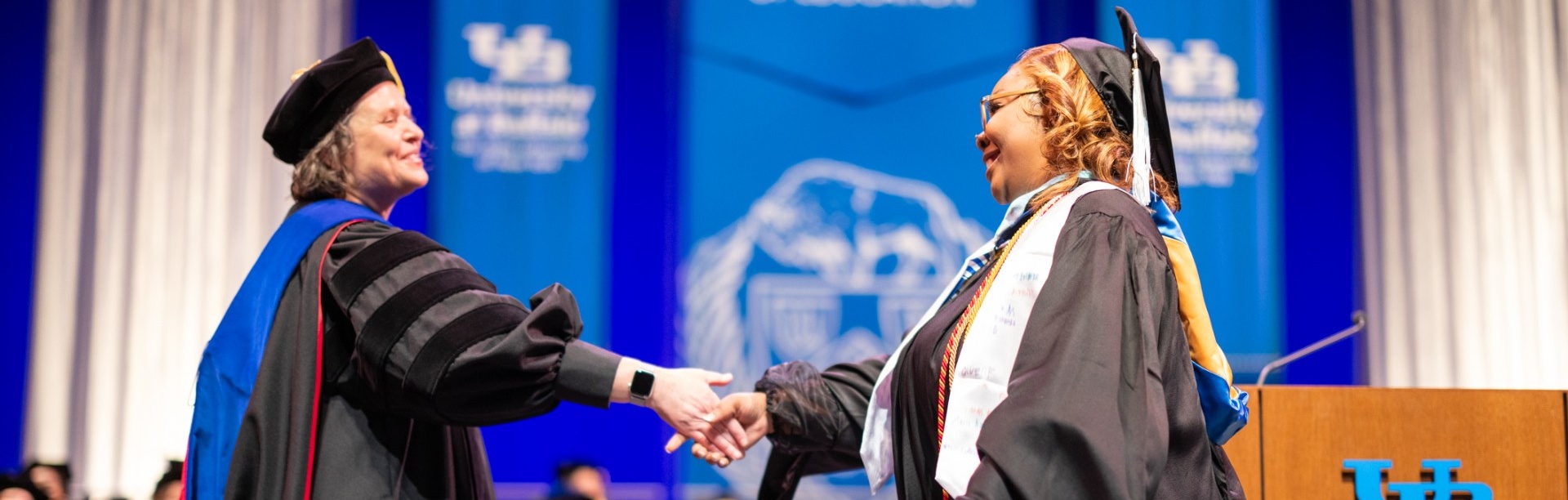 Dean of GSE shakes hands with Master's level student graduating. 