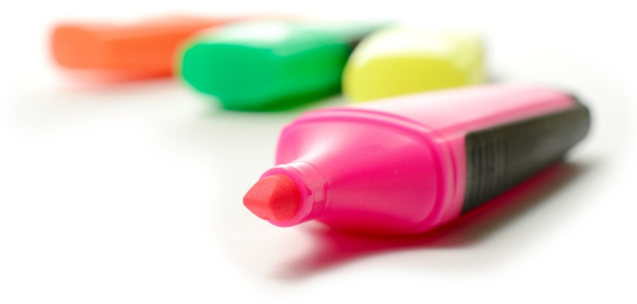 Four highlighter markers on desktop: orange, green, yellow, and the pink one is uncapped. 