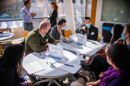 Zoom image: Several faculty members collaborating at a table