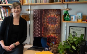GSE Associate Professor Amy Vanscoy sitting on her desk in her office. 