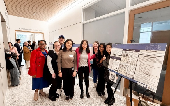 Zoom image: GSE students standing with their research posters and faculty at the student research symposium. 