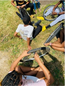 Zoom image: Children on the ground assembling bicycles. 