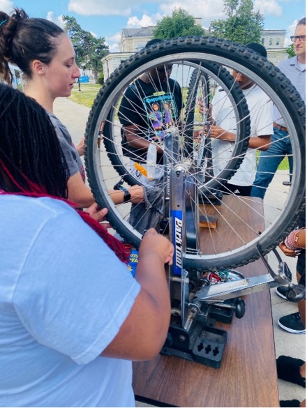 Zoom image: Children assessing a bike tire. 