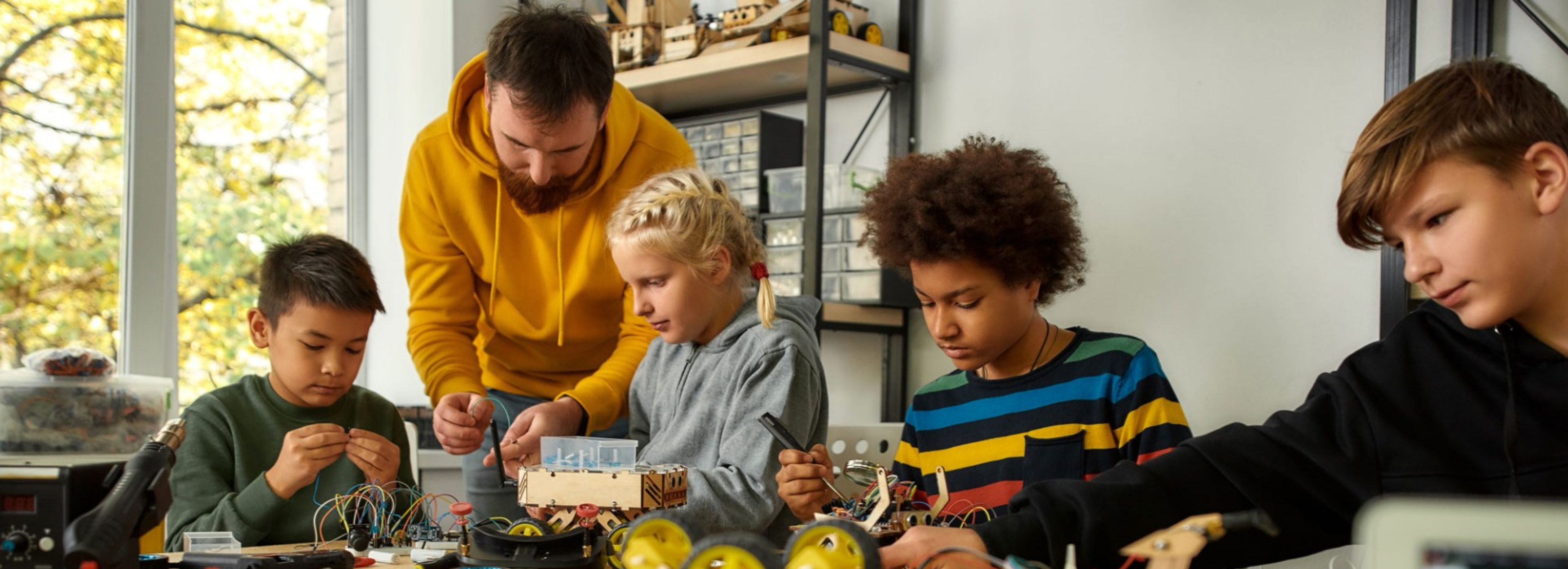 Teacher giving a science and engineering lesson to a diverse group of three students. 