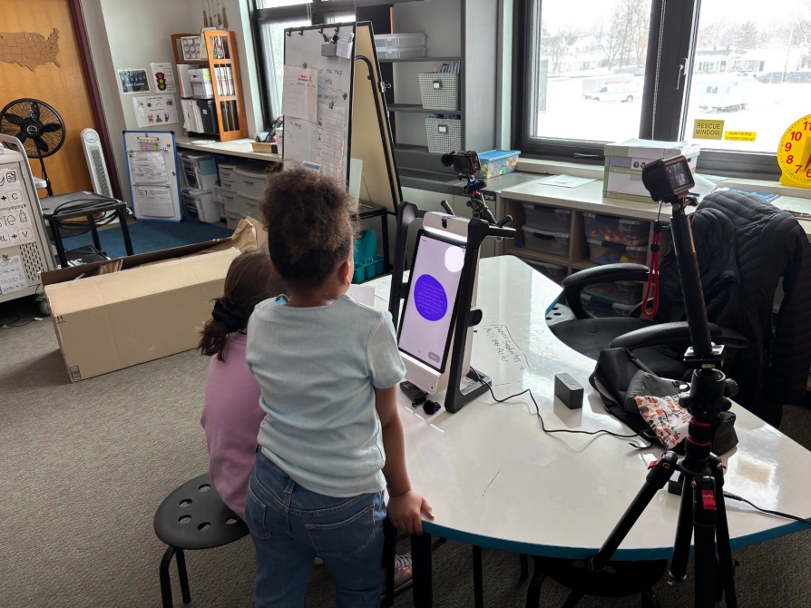 Two elementary students use the M2 device to reflect on their engineering design. The device asks what advice they would give someone beginning a similar structure and what that person should avoid based on what they learned. 