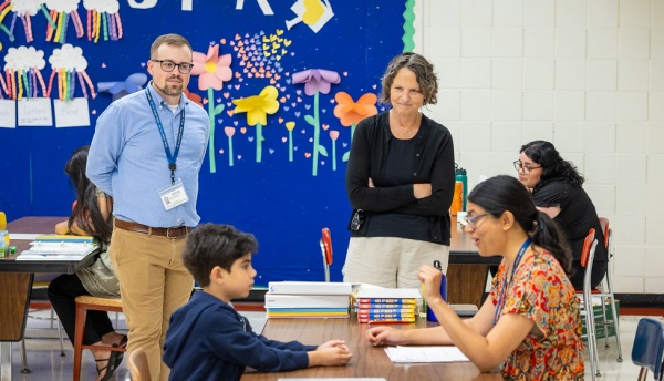 Zoom image: Suzanne Rosenblith, dean of the University at Buffalo Graduate School of Education, stands alongside John Strong, assistant professor of learning and instruction, while watching a child sitting at a classroom table interact with an educator. Photographer: Douglas Levere 