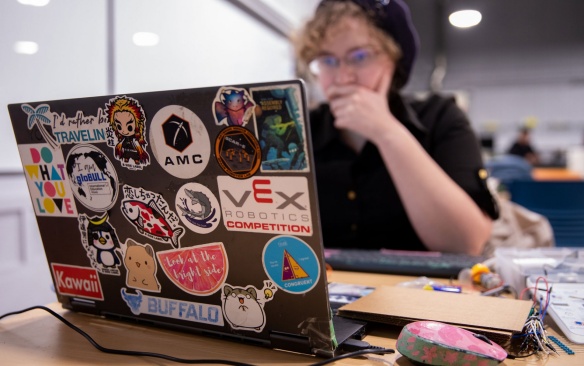 Student working at a laptop decorated with stickers. 