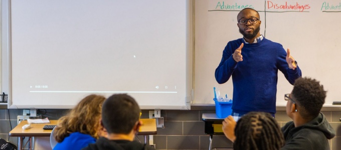 Male teacher in front of students teaching a class. 