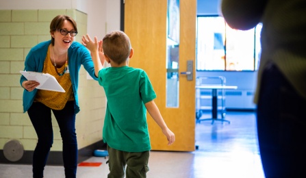 Claire Cameron high fiving a student in a school. 