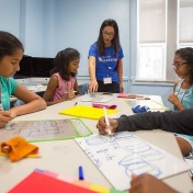 Professor Ji-Won Son works with female students in a classroom. 