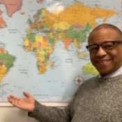 Portrait of Gary Crump in front of a world map. 