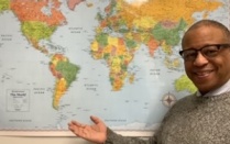 Portrait of Gary Crump in front of a world map. 