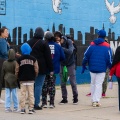 A group of people walk on a sidewalk past a mural saying "Cold Springs Strong". 