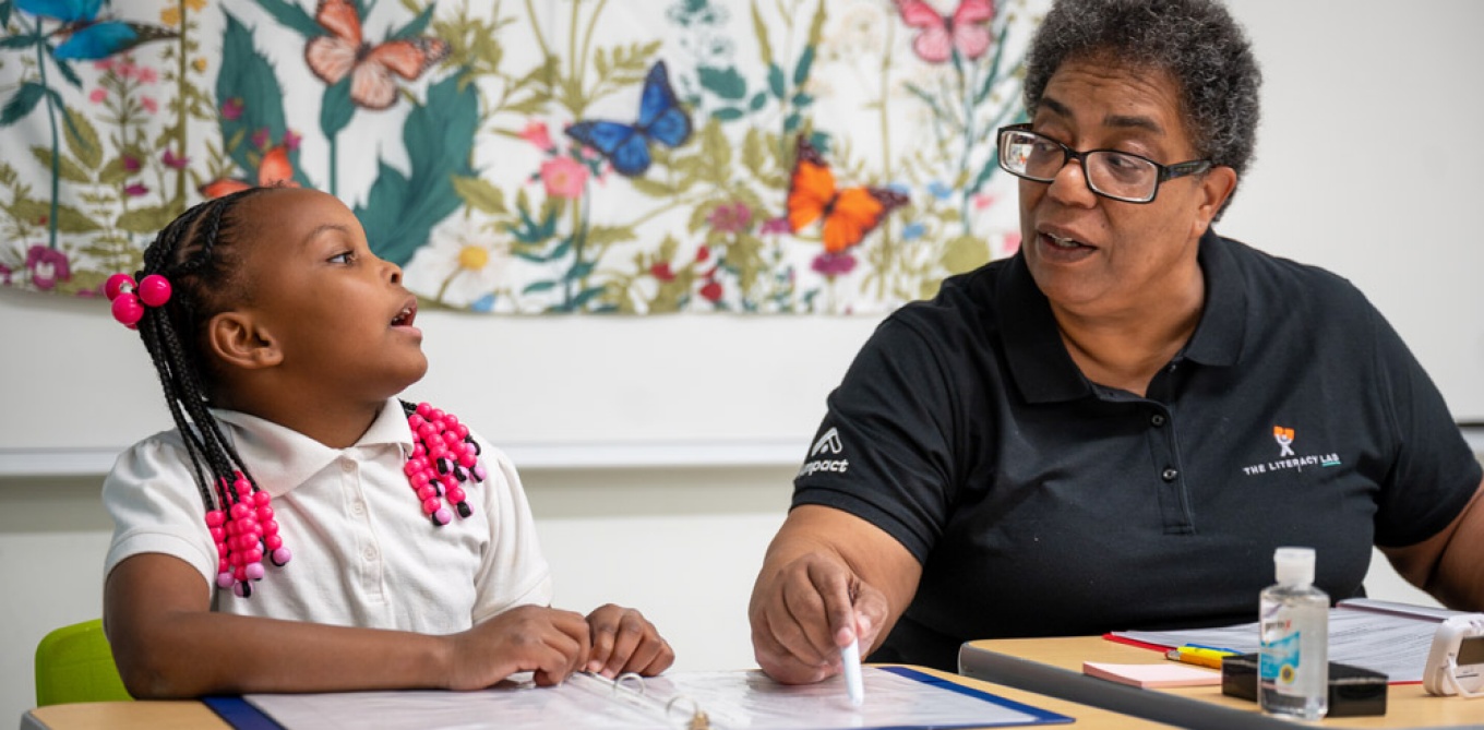 A Literacy Lab staff member working with a child in a classroom.