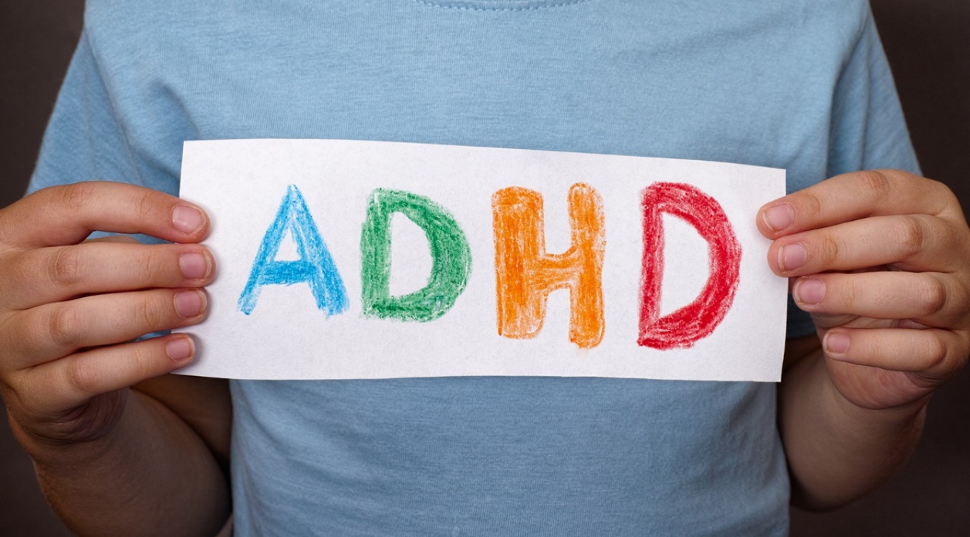Boy holding a sign with the letters ADHD.