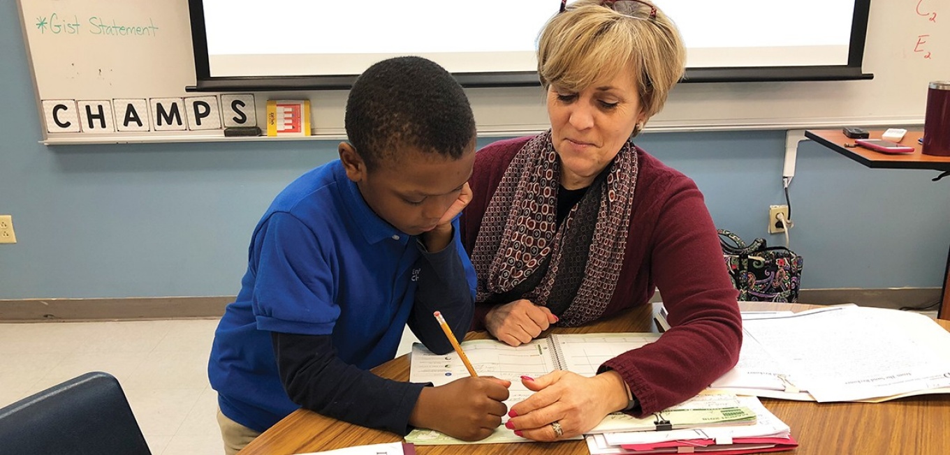 Lynn Shannahan working in a classroom with a student. 