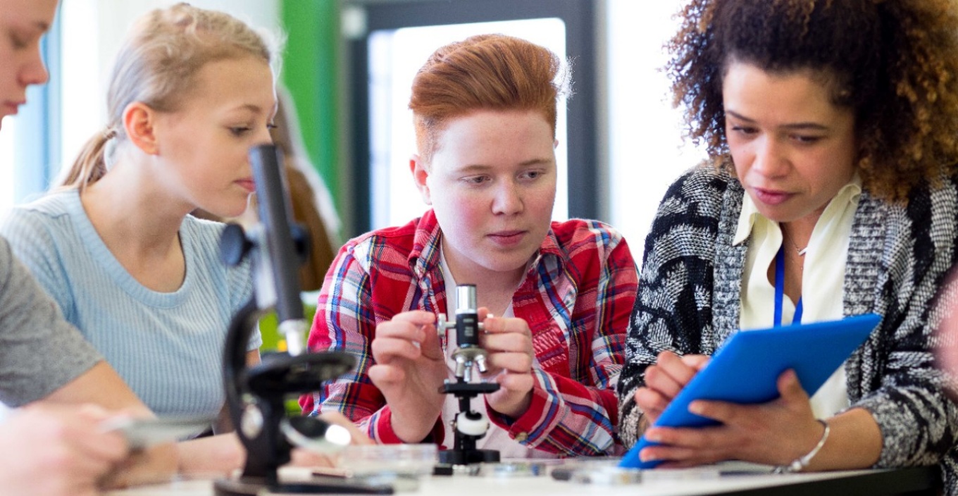 Teacher with students in science-based classroom. 