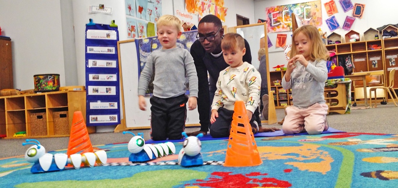 ECRC student playing with children and the Code-A-Pillar toy. 