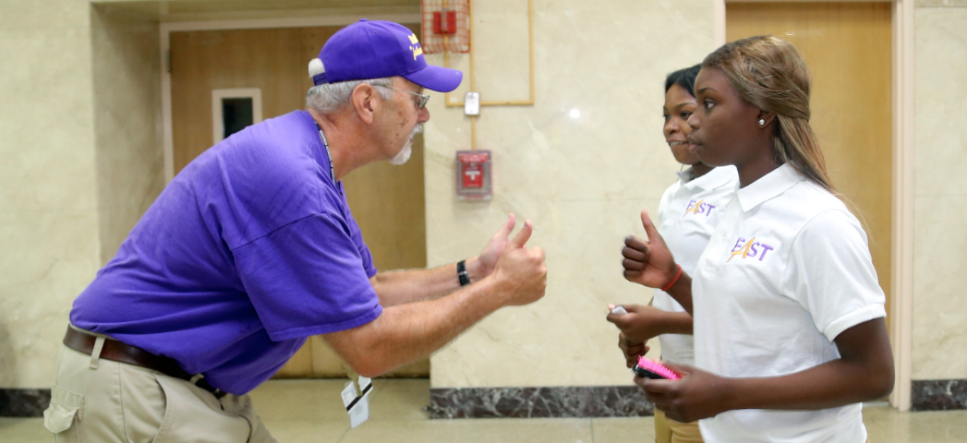 Stephen Uebbing, alumnus of the UB Graduate School of Education interacting with two East High school students. 