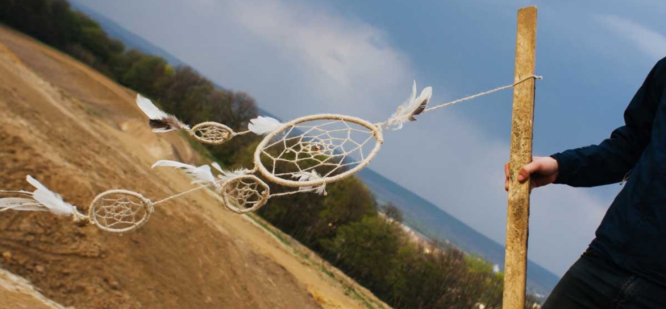 Dream catcher in the wind overlooking a hill in nature.