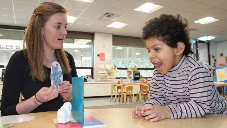 Margaret Foley, a master’s student and teacher at the Fisher Price Endowed Early Childhood Research Center, and Ethan Glasgow, 3, try a playful experiment in perception by noticing the change in a toy’s appearance when it is behind a blue screen. 