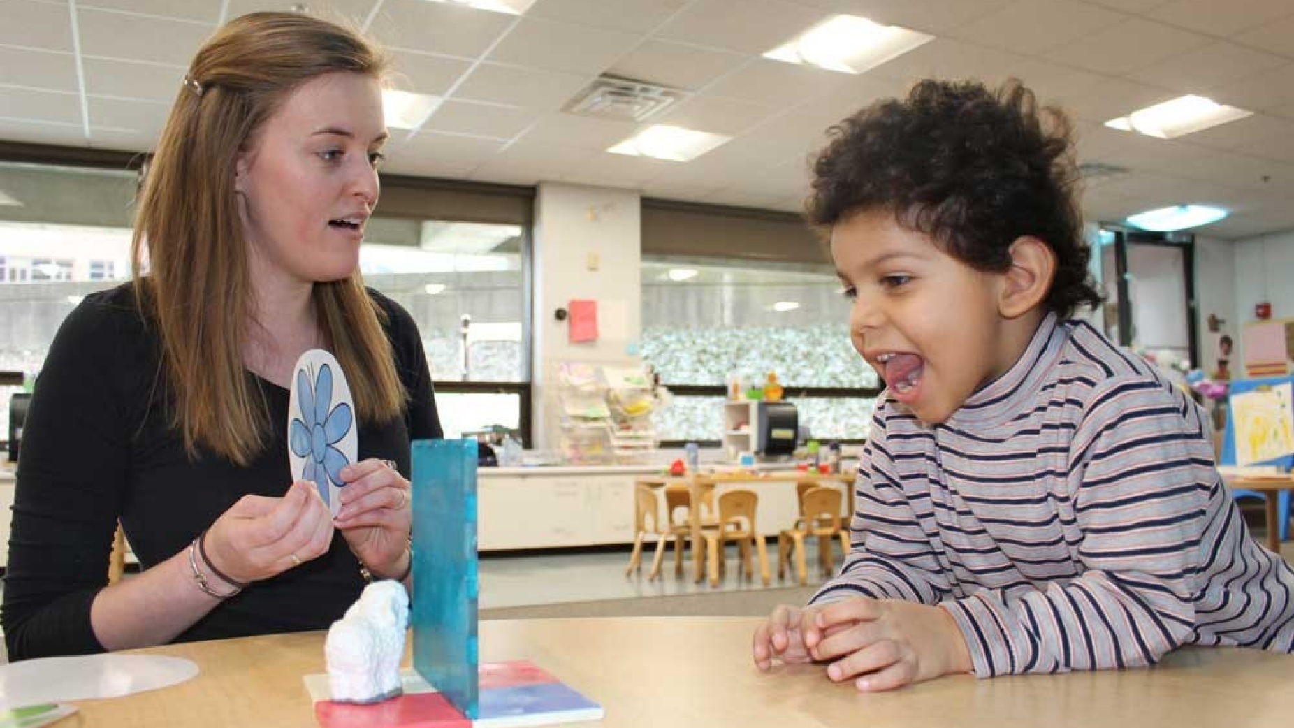 Margaret Foley, a master’s student and teacher at the Fisher Price Endowed Early Childhood Research Center, and Ethan Glasgow, 3, try a playful experiment in perception by noticing the change in a toy’s appearance when it is behind a blue screen.