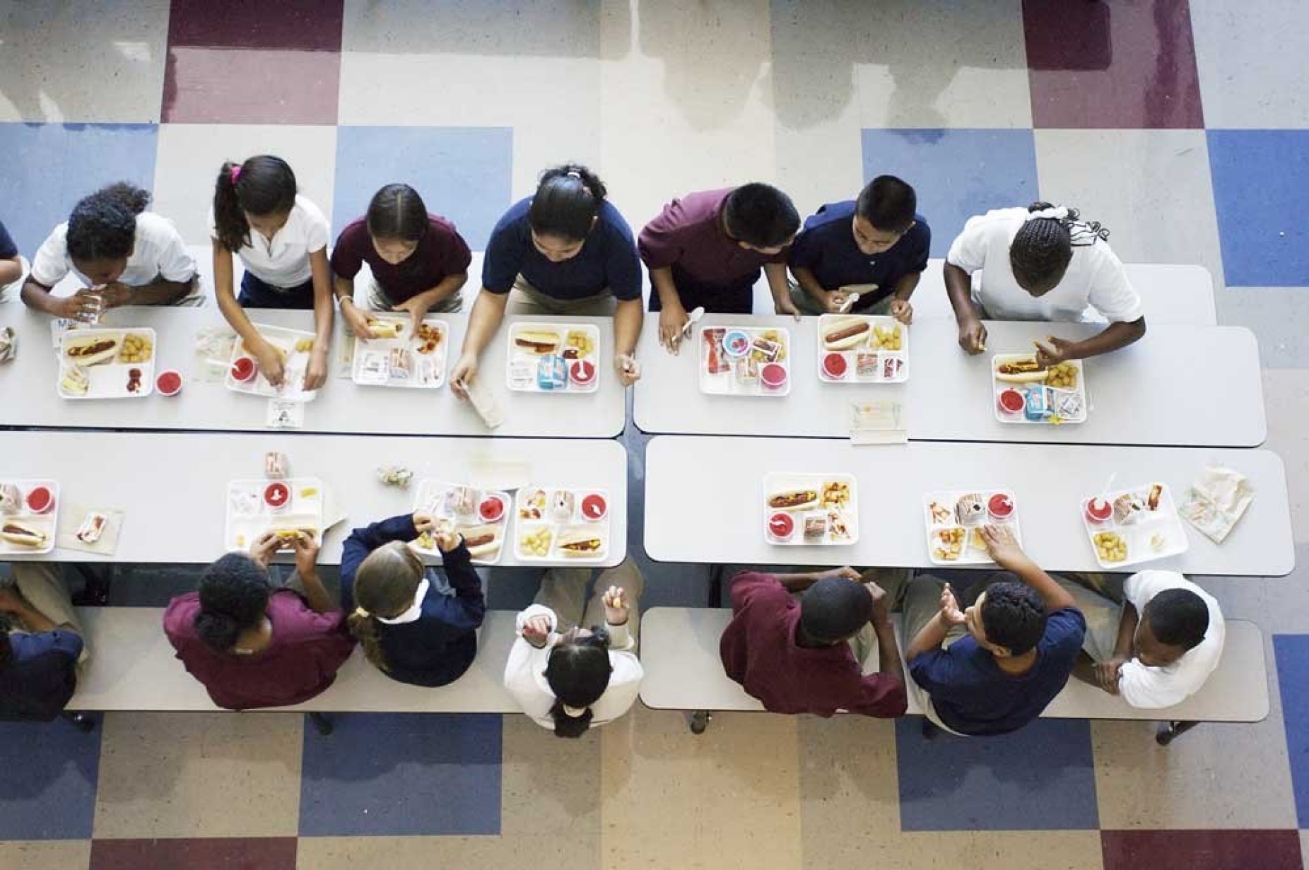 Overhead image of children eating school lunch in a cafeteria. 