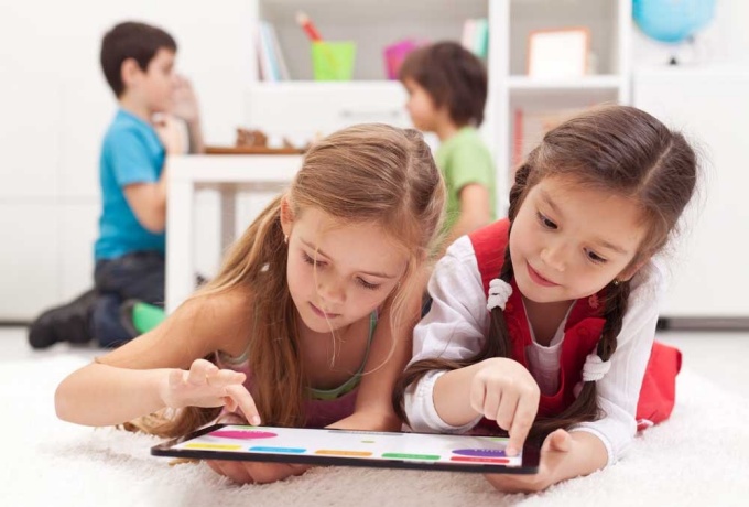 Two children learning on a tablet in a classroom. 