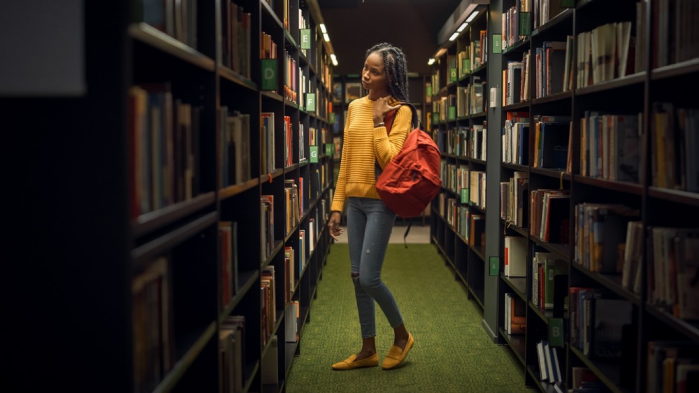 Student in library book stacks. 