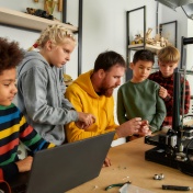 Image of a teacher working with students on a robotics project. 