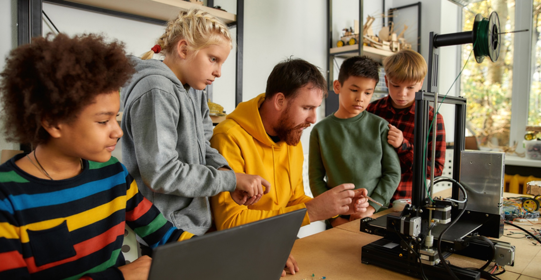 Image of a teacher working with students on a robotics project. 