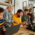 Image of a teacher working with students on a robotics project. 