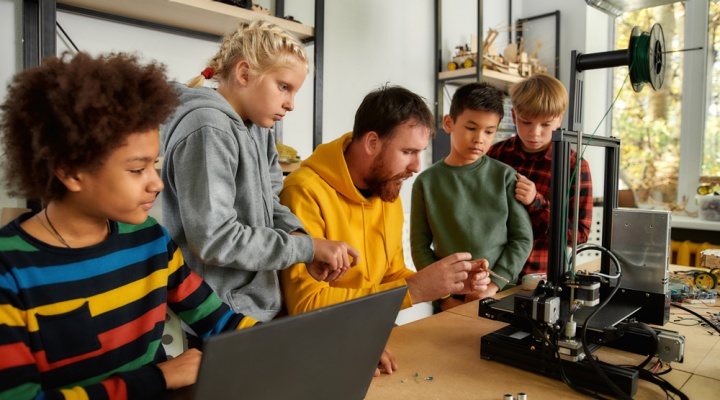 Image of a teacher working with students on a robotics project. 