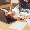 Female student taking notes at a laptop. 