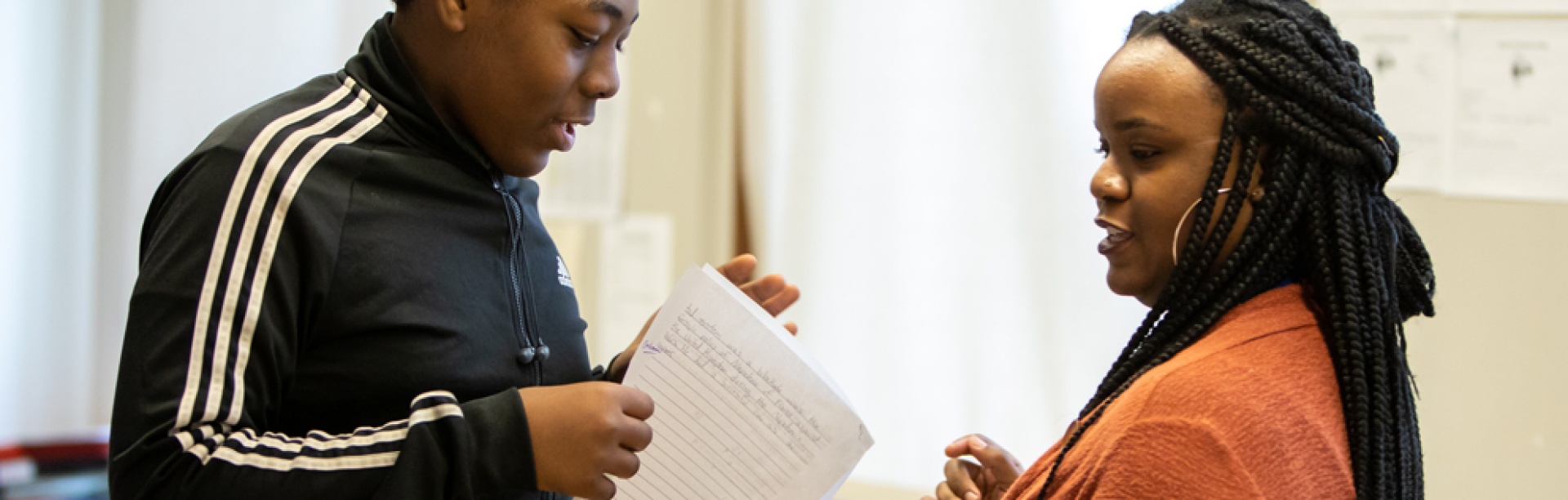 Image of a teacher working with a student in a classroom. 