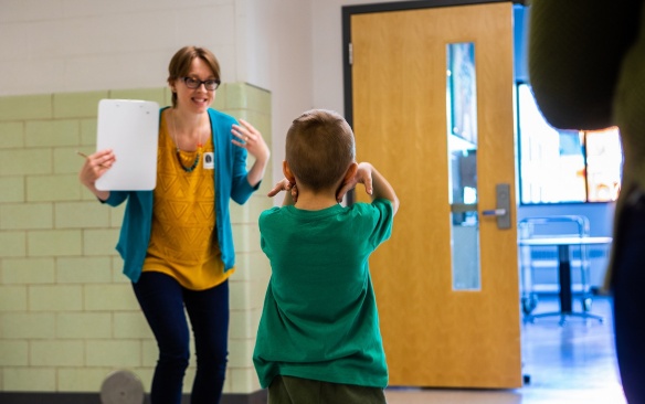 Zoom image: Claire Cameron working with a child outside of a classroom.