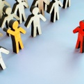 Illustration of wood figures making up a crowd with two stand out colors representing difference. 