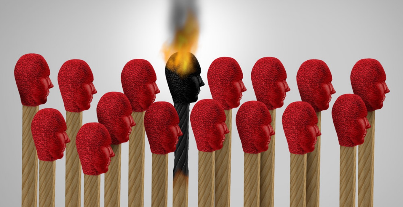 Conceptual image of matches in the shape of human heads, one lit and burning out signifying the idea of "burnout.". 