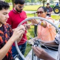 Students work on a bicycle wheel. 