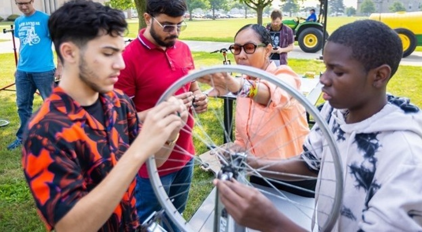 Students repair a bicycle wheel. 