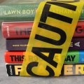 A stack of banned books with caution tape wrapped around them. 