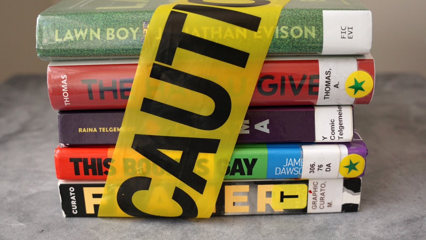 Stack of banned books with caution tape around them. 