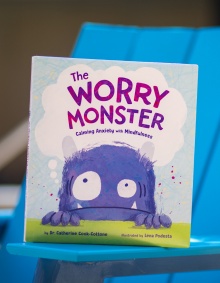 A portrait of Catherine Cook-Cottone, a professor of counseling, in the School and Educational Psychology, in the Graduate School of Education, taken in June 2024 in Paula’s Plaza on North Campus. She is photographed with her new book, “The Worry Monster.” Photographer: Meredith Forrest Kulwicki. 