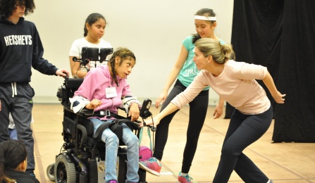 Agnes McConlogue Ferro working with a group of students. One student, in a power wheelchair, leads the group of students behind her. 