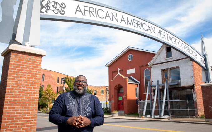 LaGarrett King standing in front of the African American Heritage Corridor. 