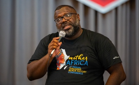 LaGarrett King speaking on a stage with a microphone. 