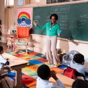 A screen grab from Abbott Elementary of a teacher speaking at a blackboard in front of her kindergarten students. 