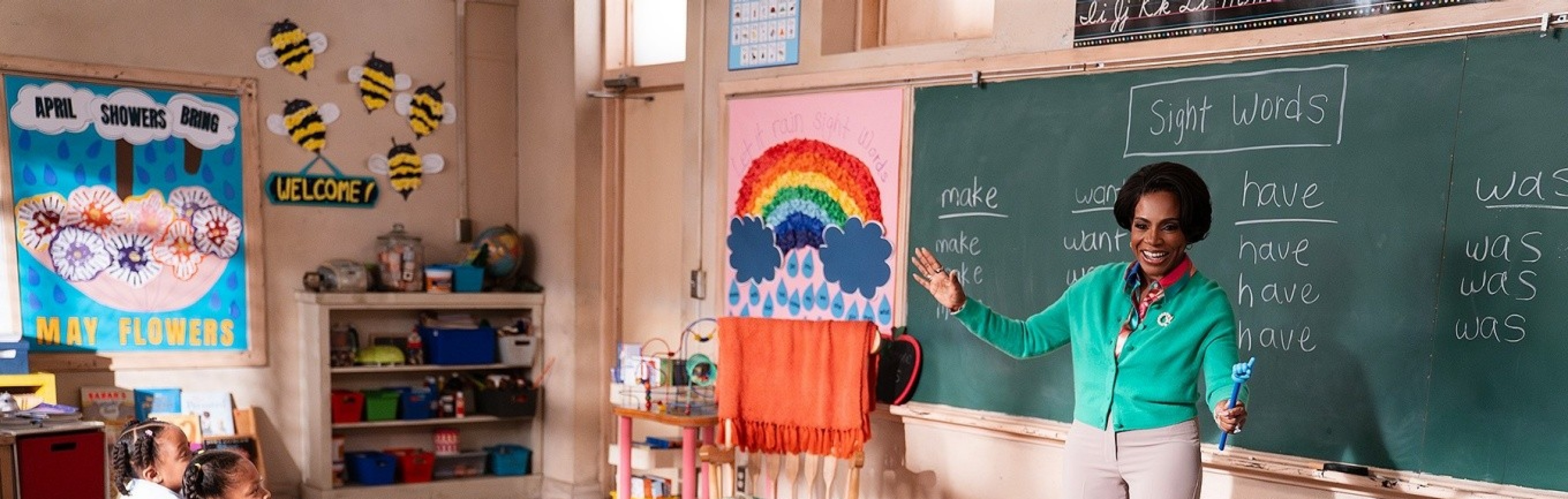 A screen grab from Abbott Elementary of a teacher speaking at a blackboard in front of her kindergarten students. 